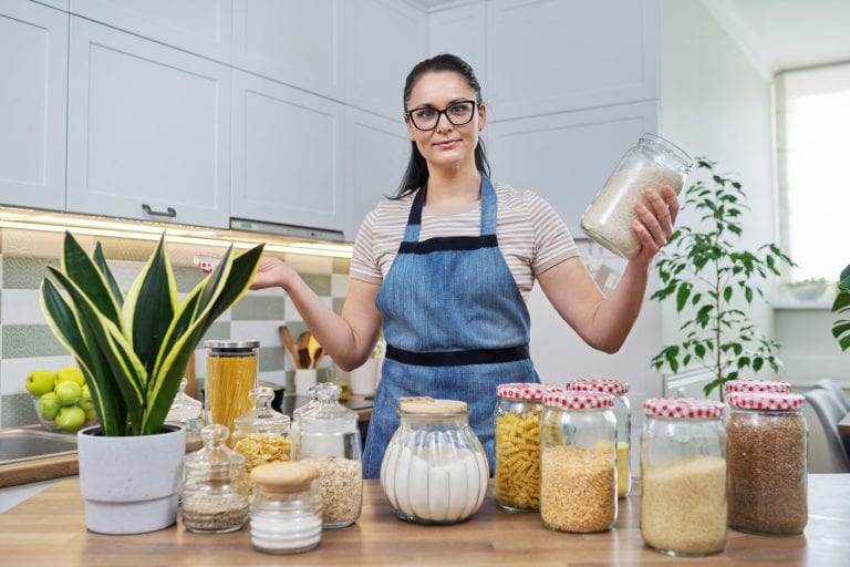 Smiling woman in the kitchen with jars of stored food.